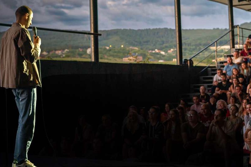Stand-up in front of the packed stands of the Summer Theatre, with the hills of Zalău behind